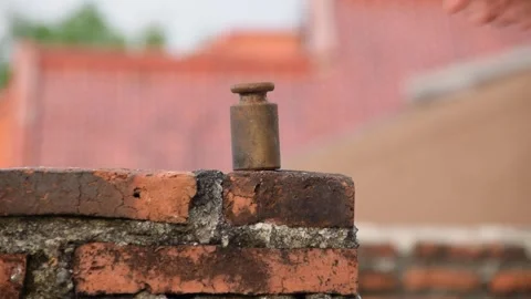 Metal scale on brick rooftop wall held by a man's hand Stock Footage 312055359