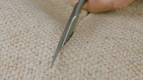 Metal scissors in the hands of the master cut the burlap fabric.. Macro shot Stock Footage 121536327