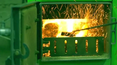 Metal scoop on long handle mixes coal in burner of coal boiler for heating Stock Footage