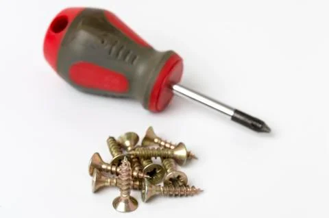 Metal screws and screw driver over white background Stock Photos