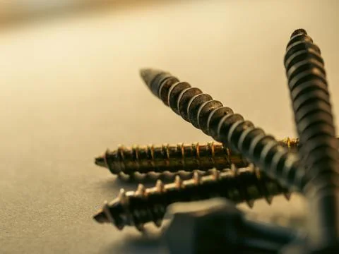 Metal screws lie close, sharp threads gleaming Stockfoto's