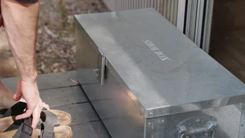 Metal shoe box outside tiny cabin with person sliding shoes off to place Stock Footage 259701147