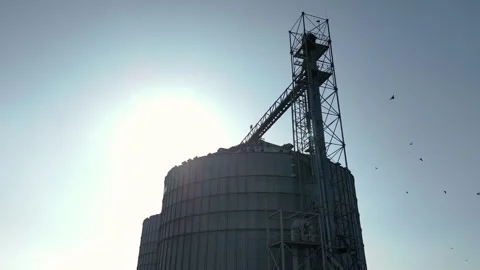Metal silo tower structure against bright sunlight with minimal sky Video stock 306099724