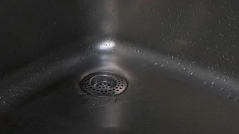 In a metal sink, drops fall from a leaking faucet. Stock Footage 150974383