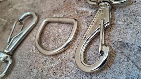 Metal snap hooks and D-rings on stone. Stainless steel hardware for bags and Stock Photos