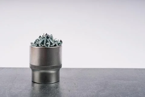 Metal socket filled with assorted screws on gray surface Foto stock