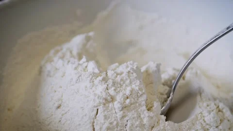 Metal Spoon Digging Into White Flour for Baking Preparation in Mixing Bowl Stock Footage 339065096