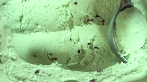 Metal spoon making cold green ice cream ball chocolate bites chips background Stock Footage 156256936