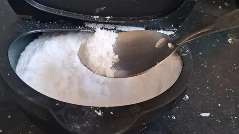 Metal spoon scooping white salt from black plastic container video Stock Footage 339302040