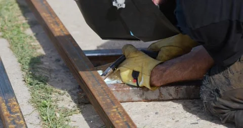 Metal steel square pipe being spot welded by hairy welder wearing gloves Stock Footage 259085331