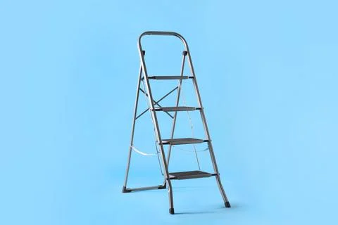 Metal stepladder on light blue background. Construction equipment 库存照片
