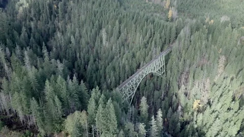 Metal structure bridge that crosses the river between two parts of the mountain Stock Footage 223363396