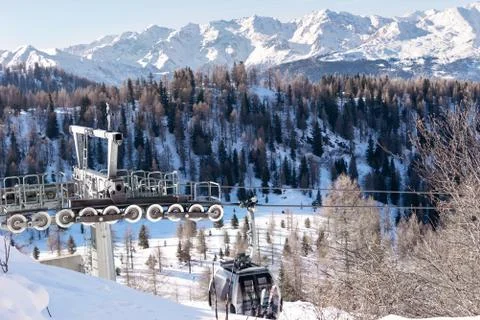 The metal structure of the cableway against the backdrop of snow-capped mount Stock Photos