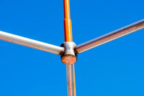 Metal structure of connected pipes in orange and silver color with fastening Stock Photos