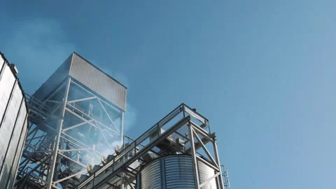 Metal structures of a grain elevator. Smoke from the pipes of a grain dryer 스톡 동영상 263064808
