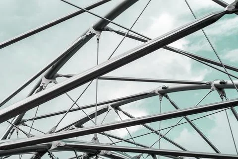 Metal structures with mesh and cables under a blue sky, forming an abstract Foto stock