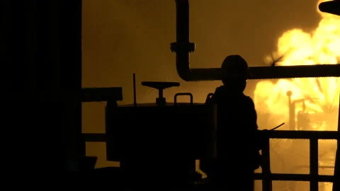 Metal structures silhouetted against the fire. The fireman passes. Engineer in a Stock Footage 148495151