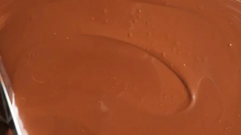 Metal table knife smoothing out glossy melted chocolate background. Stock Footage 345661050