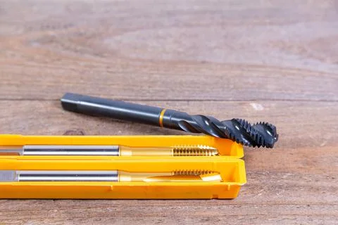 Metal threading taps. Tool for processing metal on a wooden board. Stock Photos