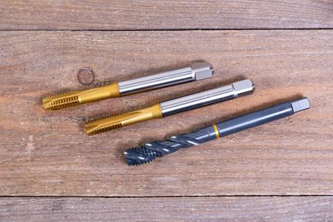 Metal threading taps. Tool for processing metal on a wooden board. Stock Photos