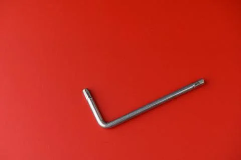 Metal tool resting on vibrant red background, showcasing its sleek design a.. Stock Photos