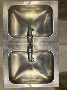 Metal train sink reflected in mirror on a compact wall Stock Photos
