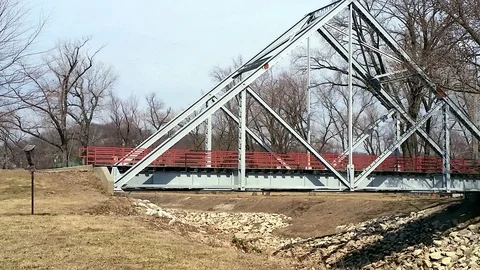 Metal triangle  pedestrian bridge over rocky river run off   panning shot Stock Footage 87186994