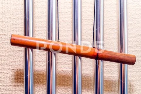 Metal tubular bells with a bamboo tube hang on the wall and create the music Stock Photos