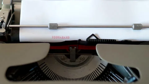 Metal typebars with red ink typing phrase BIOHAZARD WAR on white sheet paper Stock Footage 154463038