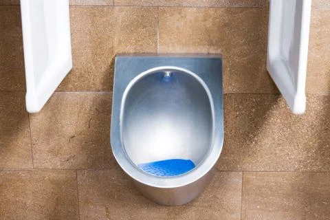 A metal urinal with an automatic flush sensor after urinating. 스톡 사진