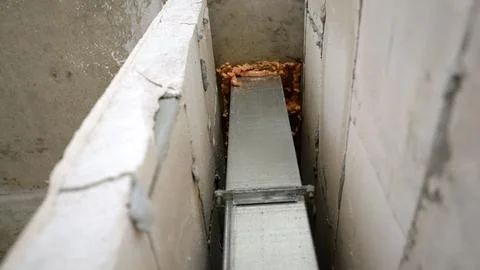 Metal ventilation duct installed between concrete blocks with expanding foa.. Stock-Fotos