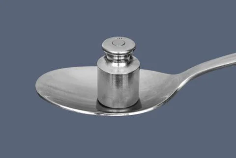 Metal weight for medical scales on the spoon isolated on gray background Stock Photos