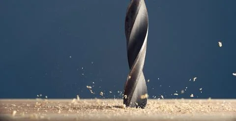 Metal wet drill bit make holes in wooden surface on industrial drilling mac.. Stock Photos
