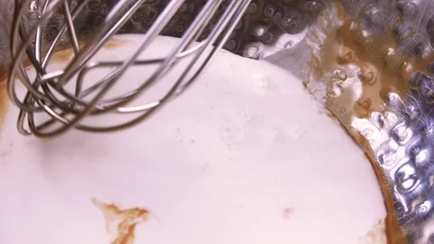 The metal whisk stirs the ingredients in a deep metallic shiny bowl. Stock Footage 79292887