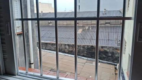 Metal window bars overlooking a view of urban roof tops Stock Photos