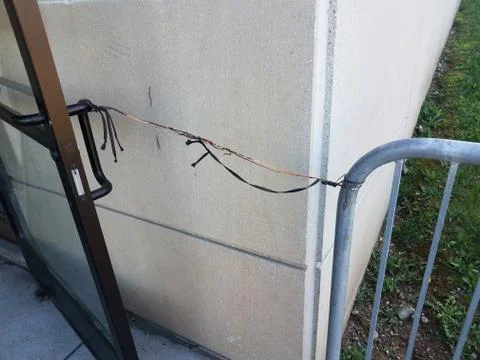 Metal wire and string holding door open and cement wall Stock Photos
