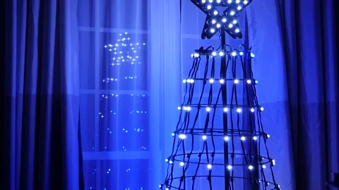 Metal wire Christmas tree at window with blue and white lights Stock Footage 259114083