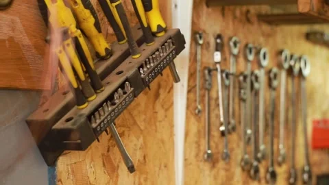 Metal wire, a set of bits, wrenches and tools hang on the wall in a repair shop Stock Footage 247020916