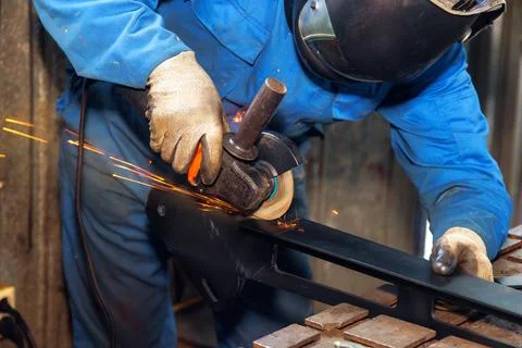 Metal worker conducting precise grinding of steel in workshop with sparks flying Stock Photos