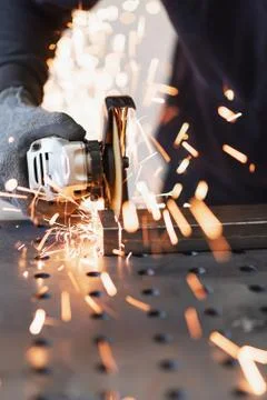 A metal worker cuts a rectangular metal pipe with an angle grinder Stock Photos