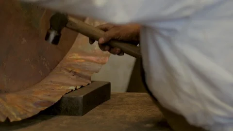 Metal worker using a ball peen hammer to shape copper in slow motion Stock Footage 98843835