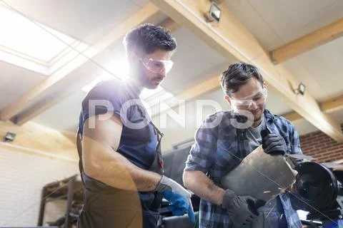 Metal workers using sander in workshop Stock Photos