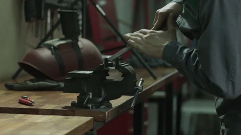 Metal workshop, worker grinding a metal pipe with a file, rasp on wooden table Stockbeeldmateriaal 74782196