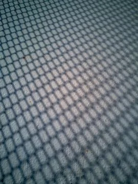 Metalic net shadow pattern on concrete pavement Stock Photos