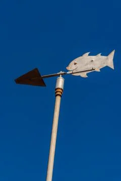Metalic vane with the shape of a fish with a clean blue sky background Stock Photos