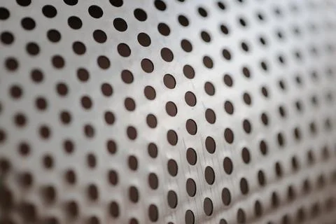 Metallic background texture with a precise pattern of dark circular perforations 库存照片