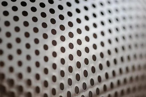 Metallic background texture with a precise pattern of dark circular perforations 库存照片