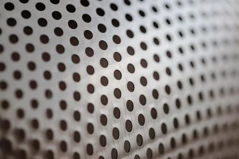 Metallic background texture with a precise pattern of dark circular perforations Stock Photos