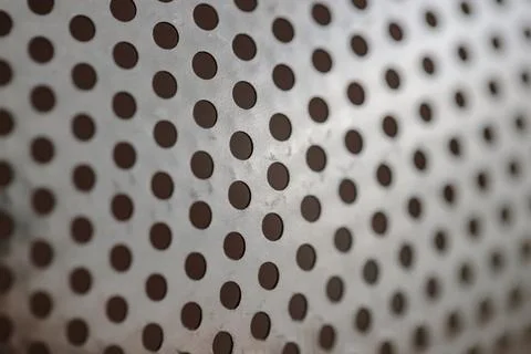 Metallic background texture with a precise pattern of dark circular perforations 库存照片