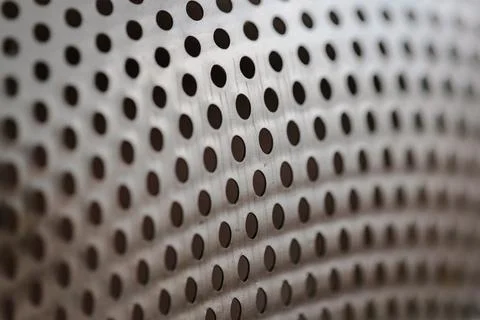 Metallic background texture with a precise pattern of dark circular perforations Stock Photos